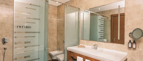 A modern bathroom with a glass shower enclosure, a wooden vanity, a large mirror, and a toilet.