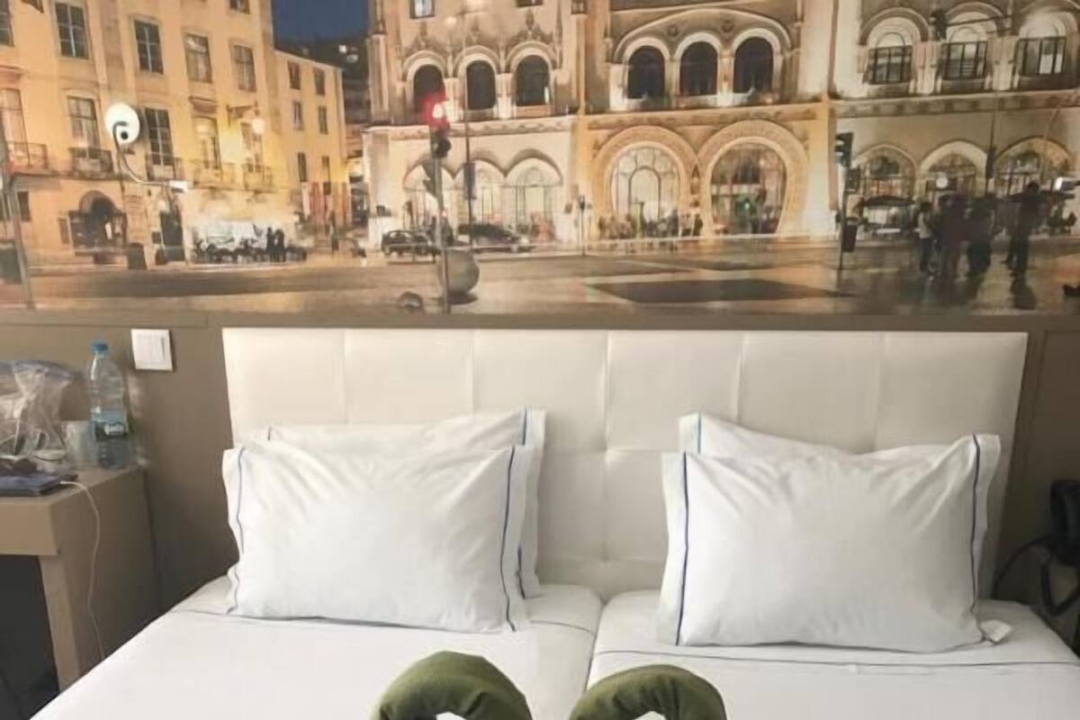 A hotel room with a bed, pillows, and a heart-shaped towel arrangement.