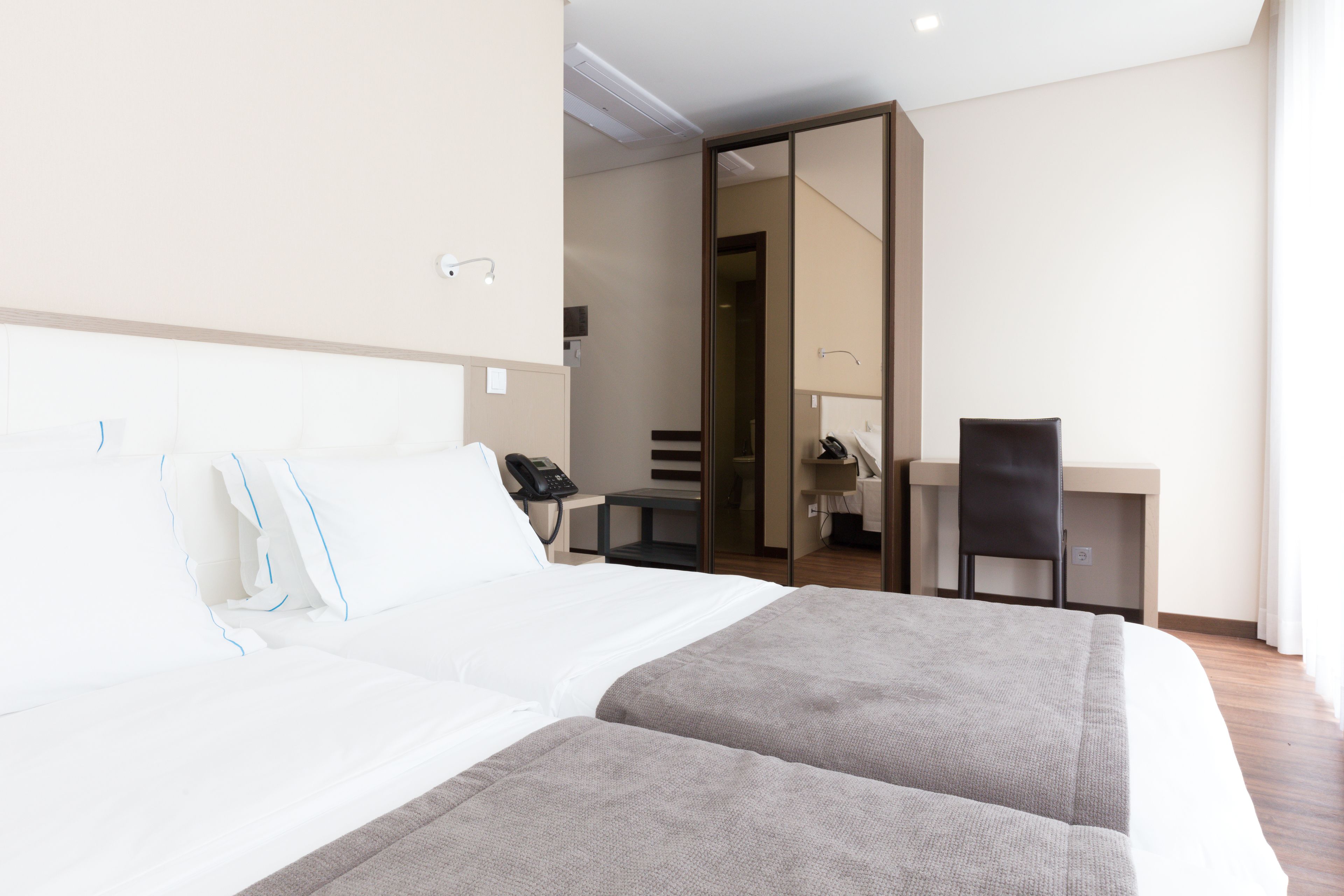 A hotel room with a bed, a desk, and a chair.