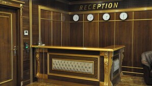 A reception area with a wooden reception desk, four clocks, and a leather chair. - Joyy Hotel & Spa (Baku)