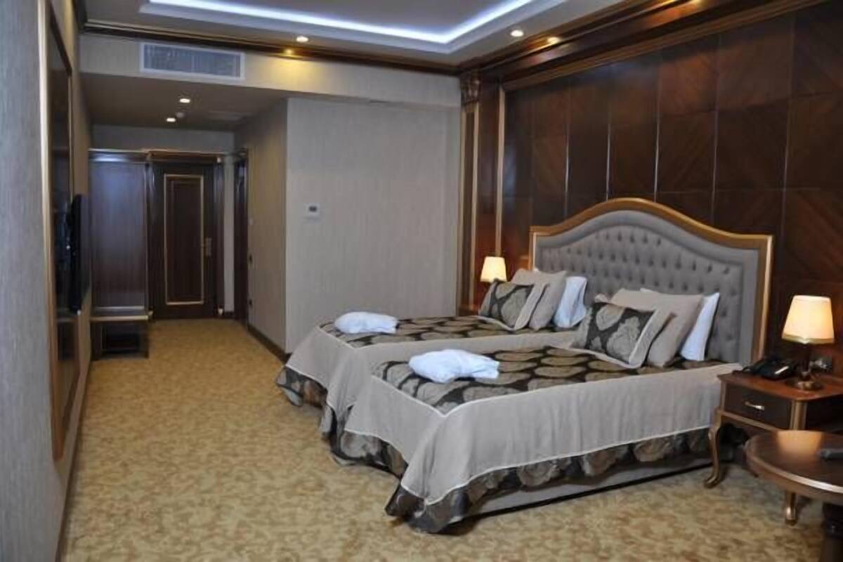 A hotel room with a large bed, two bedside tables, a nightstand, and a carpeted floor.