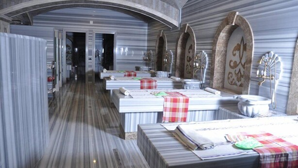 A hotel room with a marble floor, a large arched doorway, and a bed with a checkered bedspread. - Joyy Hotel & Spa (Baku)