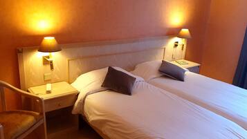 A hotel room with a double bed, two bedside tables with lamps, a chair, and a nightstand.