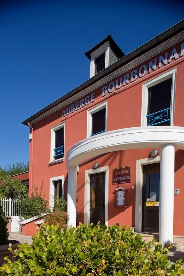 Un edificio rojo con el letrero 'AUBERGE BOURBONNAISE' que indica un hotel.