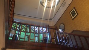 A staircase with wooden railings and a view of a room with a patterned wall and a ceiling fan.