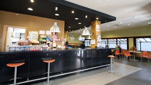 A restaurant interior with a counter, bar stools, and seating area.
