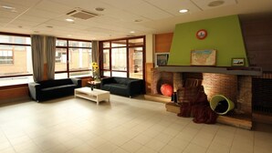 A spacious lobby with a fireplace, two sofas, a coffee table, and large windows.
