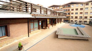 A hotel with a pool, outdoor seating, and a covered area with a view of the pool.