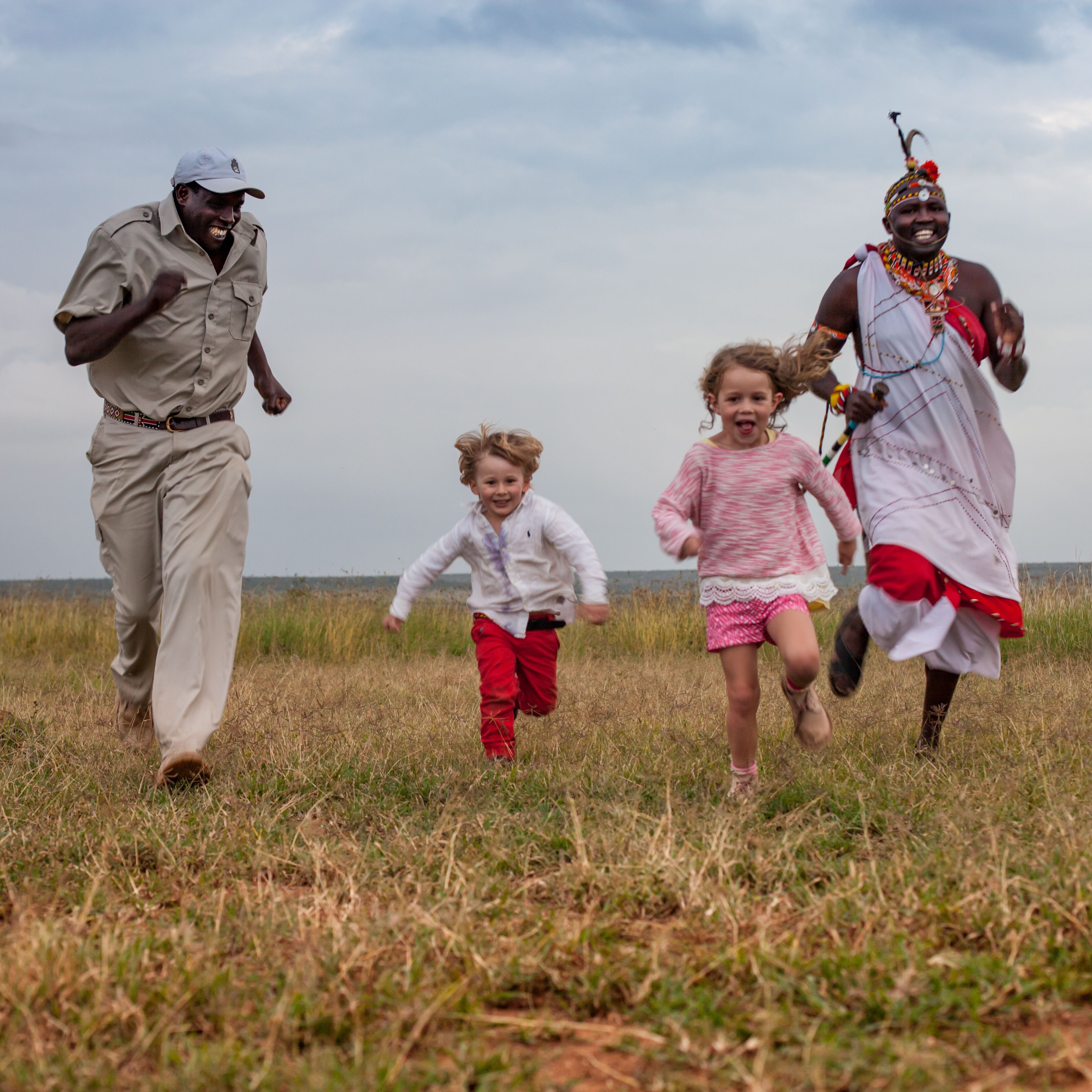A family running in a grassy field.