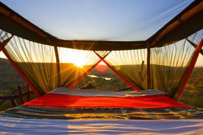 A tent with a bed inside, set against a backdrop of a sunset. - Elewana Loisaba Star Beds (Loisaba)
