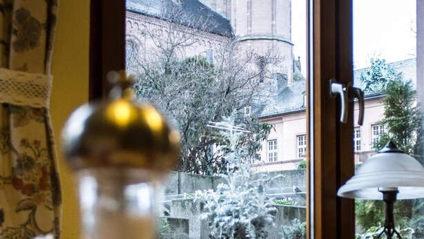 A room with a window overlooking a historic building with towers. - Hotel Kriemhilde (Worms)