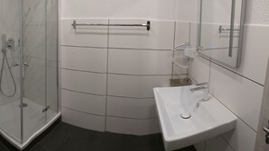A modern bathroom with a toilet, shower, and sink. - Hotel Kriemhilde (Worms)