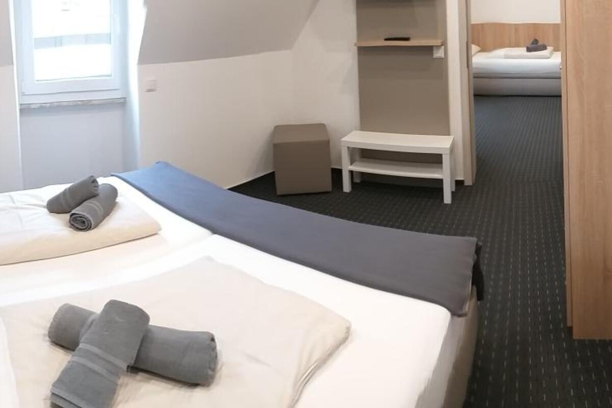 A hotel room with a bed, a small table, and a chair.