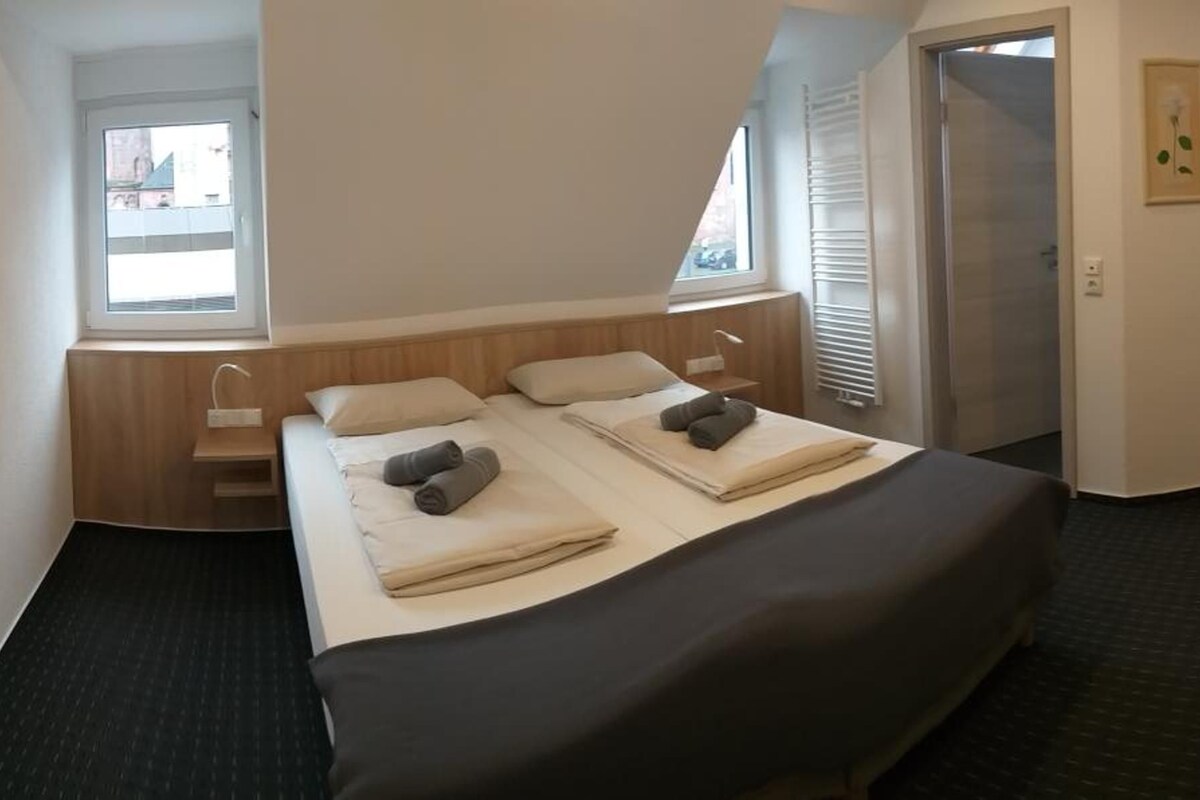 A hotel room with a bed, a desk, a chair, and a television.