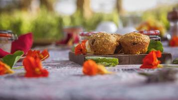 Dos muffins sobre una tabla de madera con flores rojas y hojas verdes en una mesa.