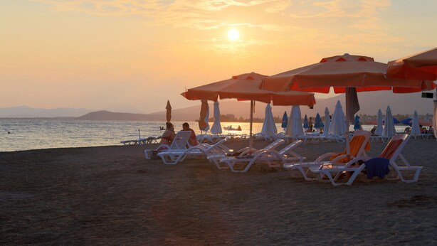 A beach with sun loungers and umbrellas, a sunset, and a calm sea. - Pansion Akrogiali (Eretria)