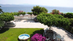 A patio with a pool, seating area, and a view of the sea. - Pansion Akrogiali (Eretria)