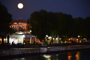 A waterfront restaurant with outdoor seating, a view of the water, and a full moon in the sky. - Pansion Akrogiali (Eretria)