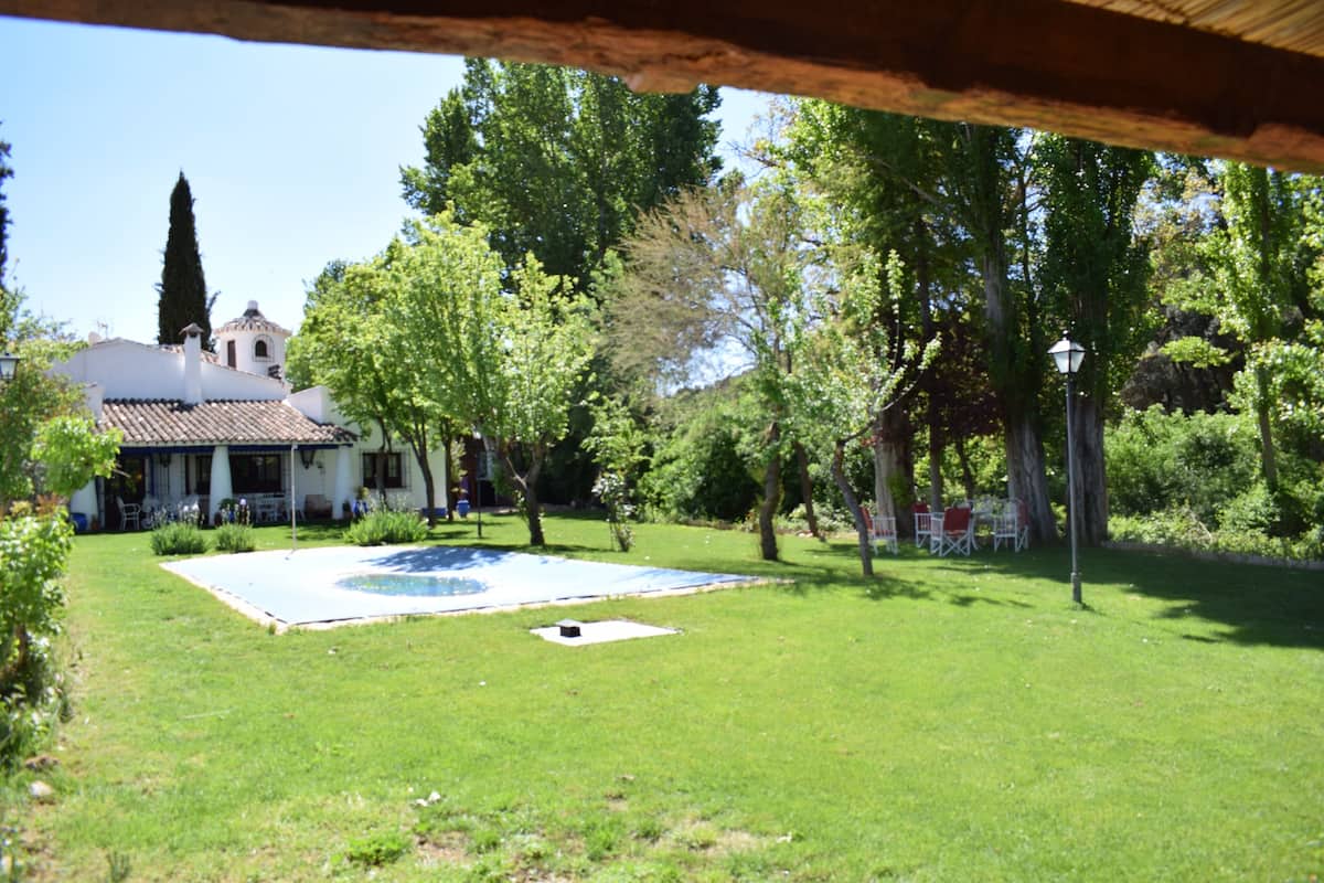 Un patio con piscina, rodeado de árboles y un edificio con tejado de cerámica.