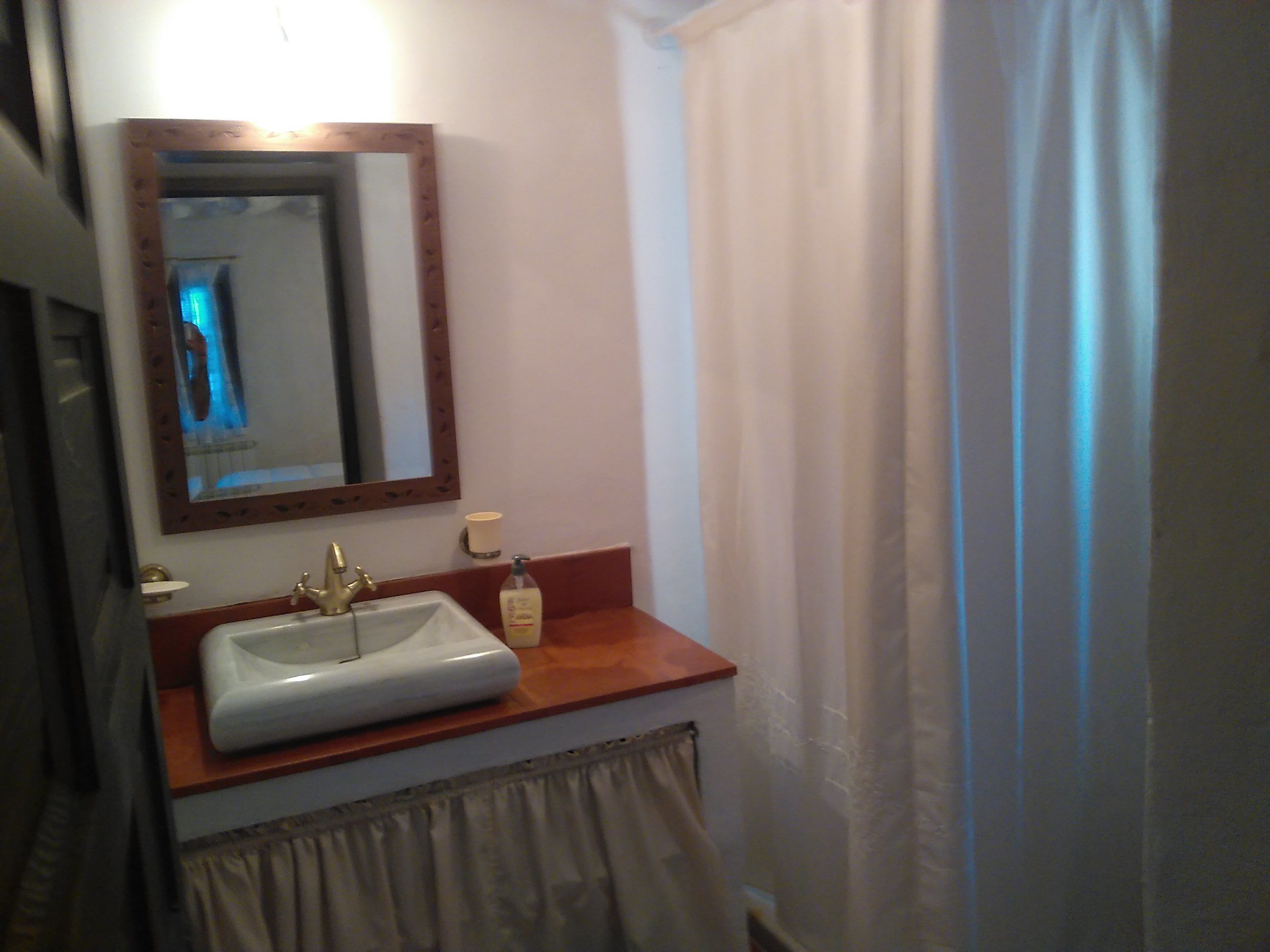 Ein Badezimmer mit Waschbecken, Spiegel und einer Handseifenflasche.