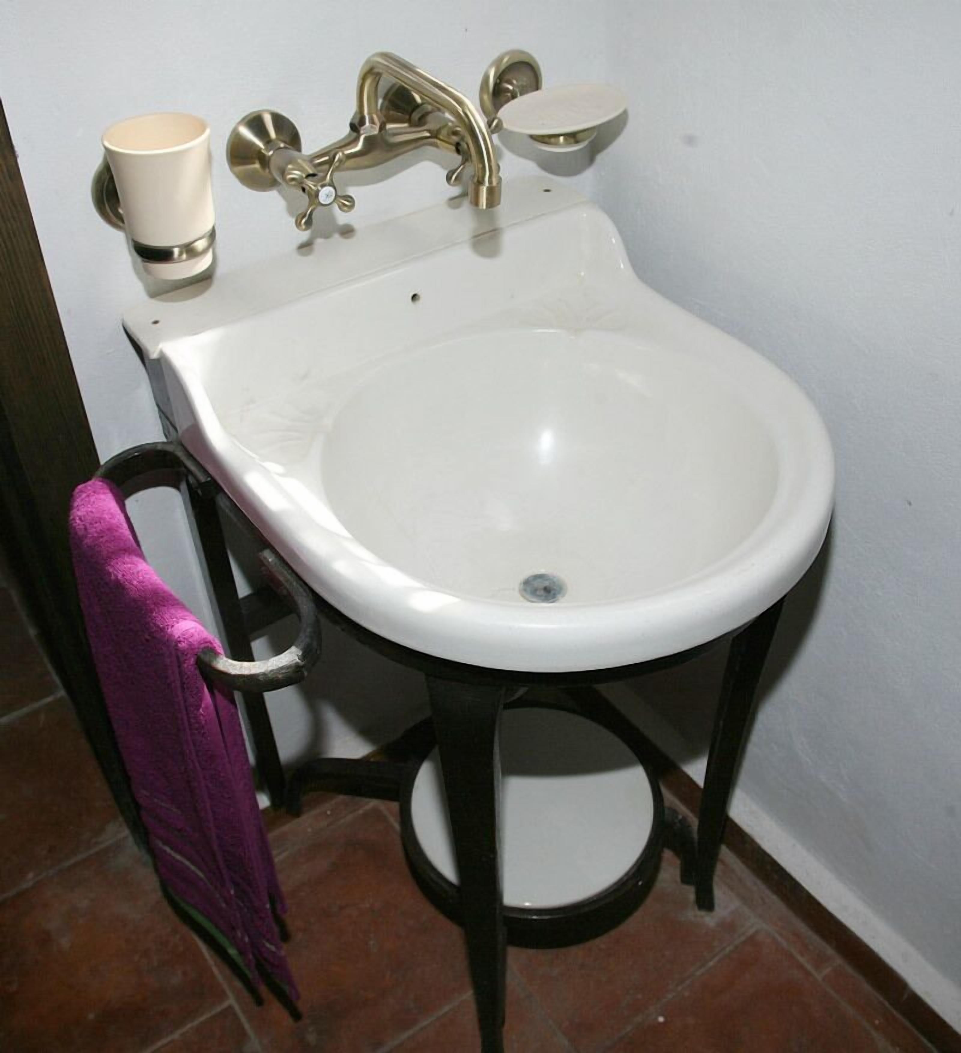 A white pedestal sink with a single faucet and a soap dish.