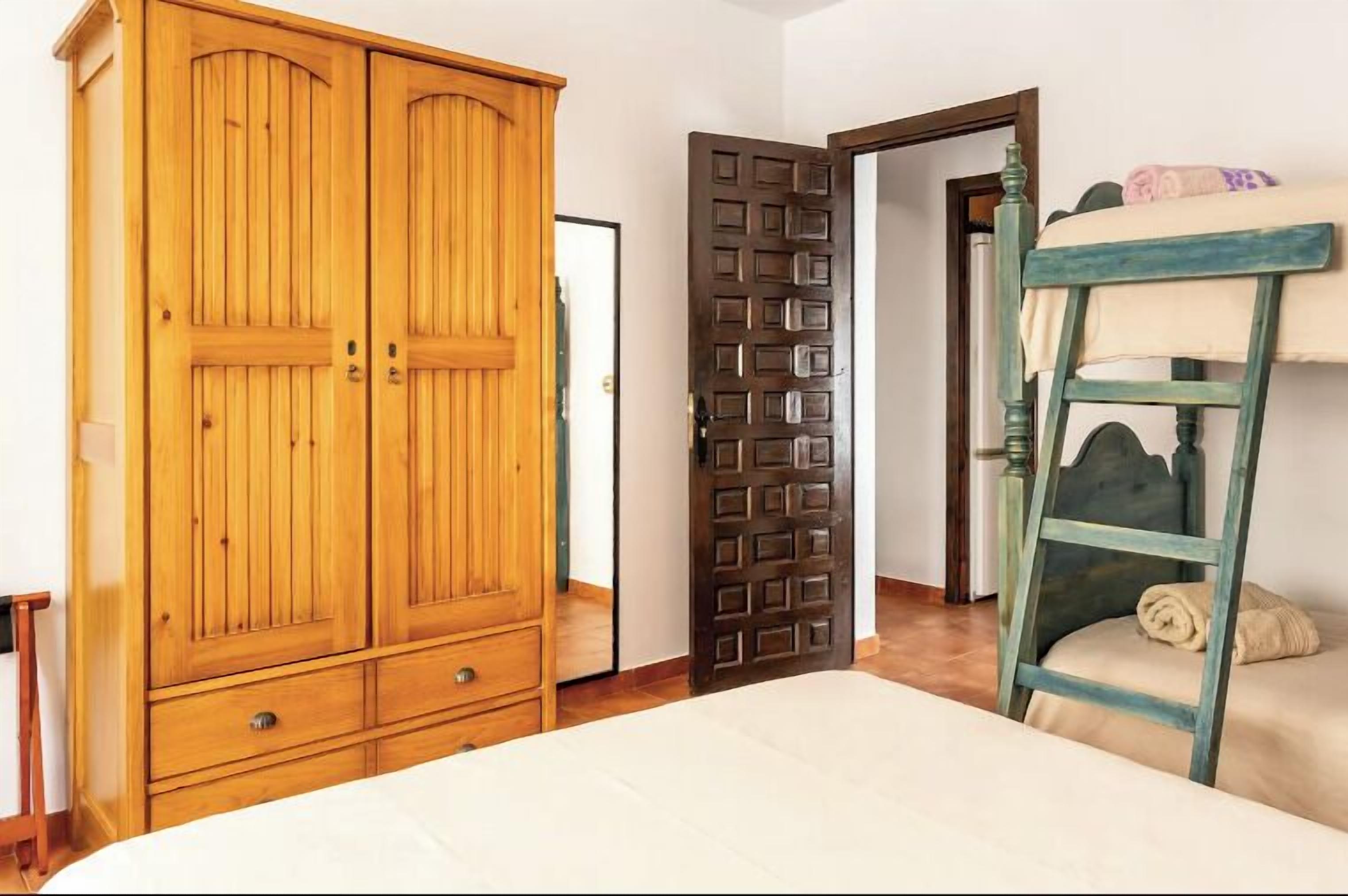 Una camera da letto con un armadio in legno, un letto a castello e una porta.