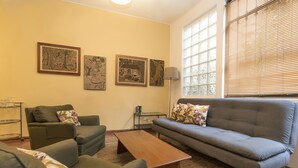 Una sala de estar con sofá, sillones, una mesa de centro y obras de arte en la pared.