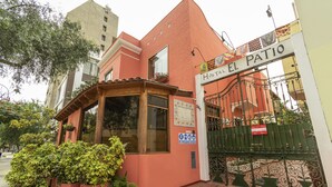 Un edificio con un letrero que dice "Hostal El Patio" y una entrada con reja.