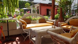 Un patio con mobiliario de mimbre, incluyendo un sofá y sillones, además de una mesa.