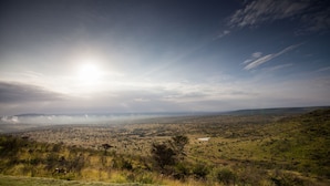 A panoramic view of a landscape with a river, distant mountains, and a clear sky.