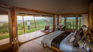 A bedroom with a large bed, a wooden floor, and a view of the outdoors.
