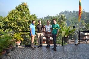 Four people standing on a terrace with potted plants and a flag. - A&B events (Matale)