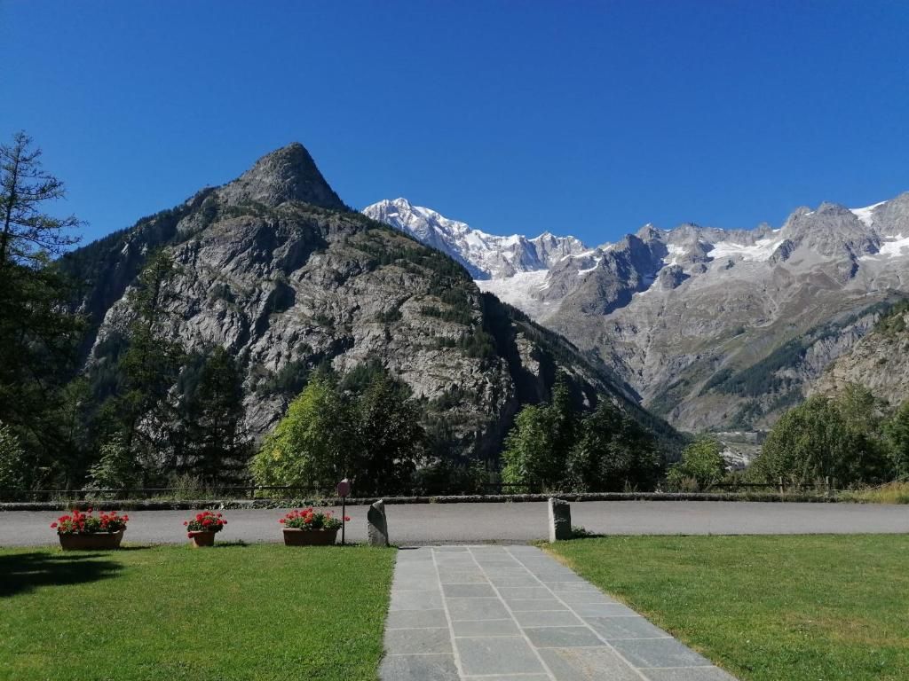 Un sendero pavimentado que conduce a una vista de la montaña, con un pico rocoso y montañas nevadas al fondo.
