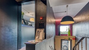 Un ascenseur moderne doté d’un clavier, un petit bureau avec un livre et un stylo, et un objet décoratif posé sur le dessus.