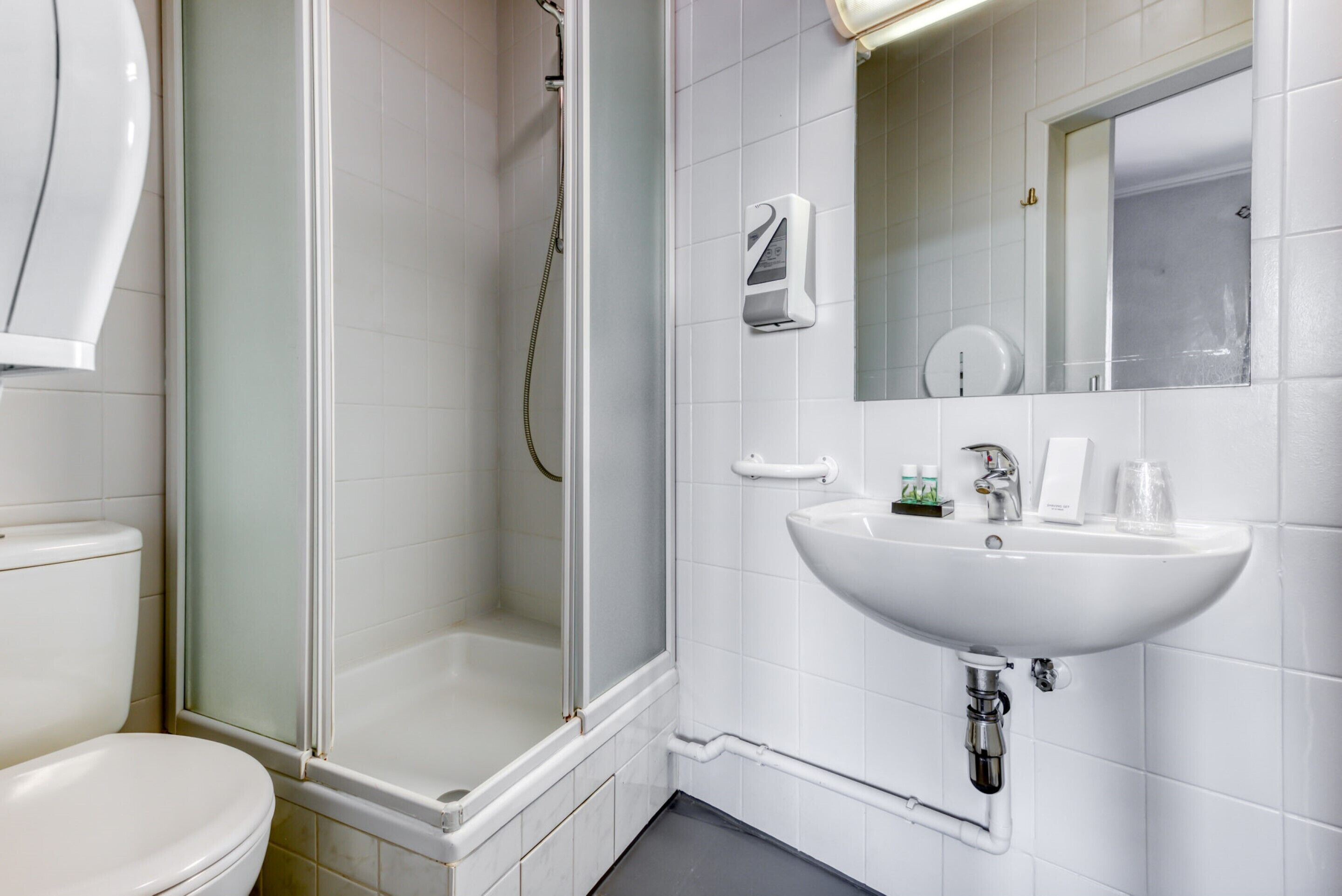 Un baño moderno con ducha de vidrio, un lavamanos blanco y un inodoro.
