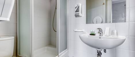Un baño moderno con ducha de vidrio, un lavamanos blanco y un inodoro.