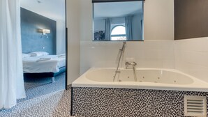 Une salle de bain moderne avec une grande baignoire, une douche et un miroir au-dessus de la baignoire.