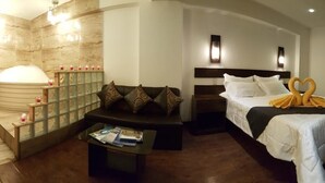 A hotel room with a bed, a sofa, a small table, a bathtub, and a TV. - La Cabaña Hotel (Cusco)