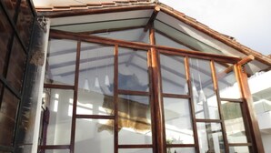 A conservatory with a glass roof, wooden beams, and a sofa inside. - La Cabaña Hotel (Cusco)