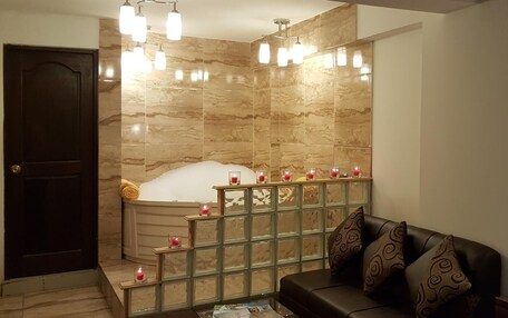 A modern bathroom with a bathtub, a glass partition, and a seating area with a sofa and cushions.