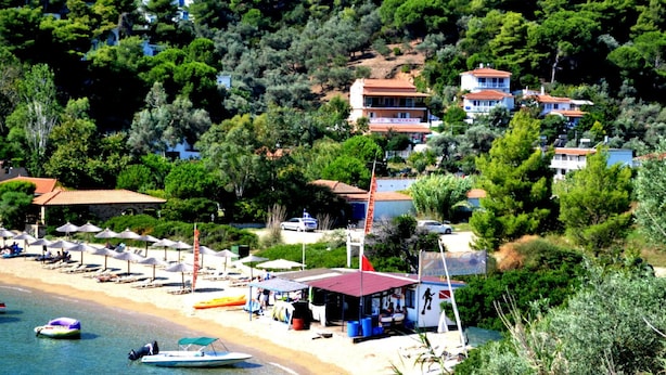 A coastal area with a beach, umbrellas, and boats.