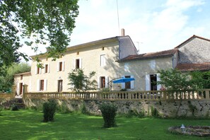 Traditional stone building with a symmetrical facade and manicured garden.