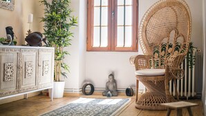 Une pièce comprenant un meuble en bois, une chaise en osier, une plante en pot et une statue de Bouddha.
