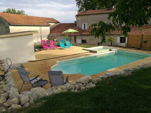 Relax by the pool surrounded by a deck with lounge chairs and a table.