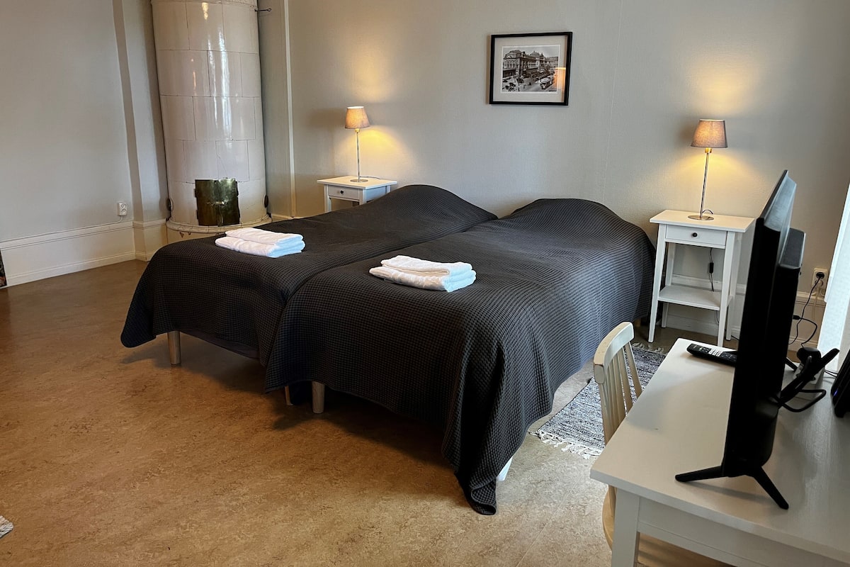 Une chambre d’hôtel avec deux lits, un bureau avec un ordinateur et une grande fenêtre.
