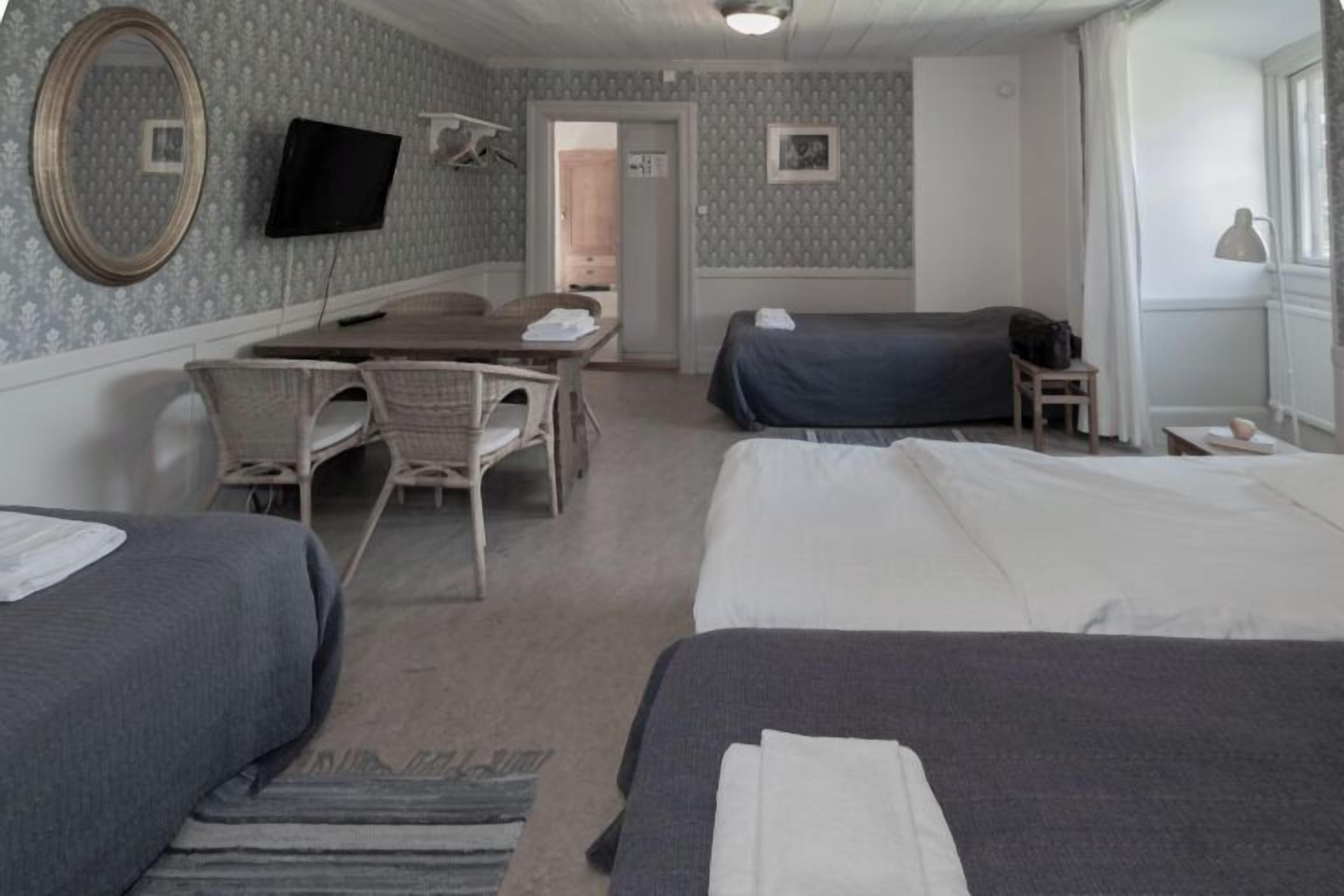 Ein Hotelzimmer mit zwei Betten, einem Schreibtisch, einem Stuhl, einem Fernseher und einem Fenster mit Vorhängen.