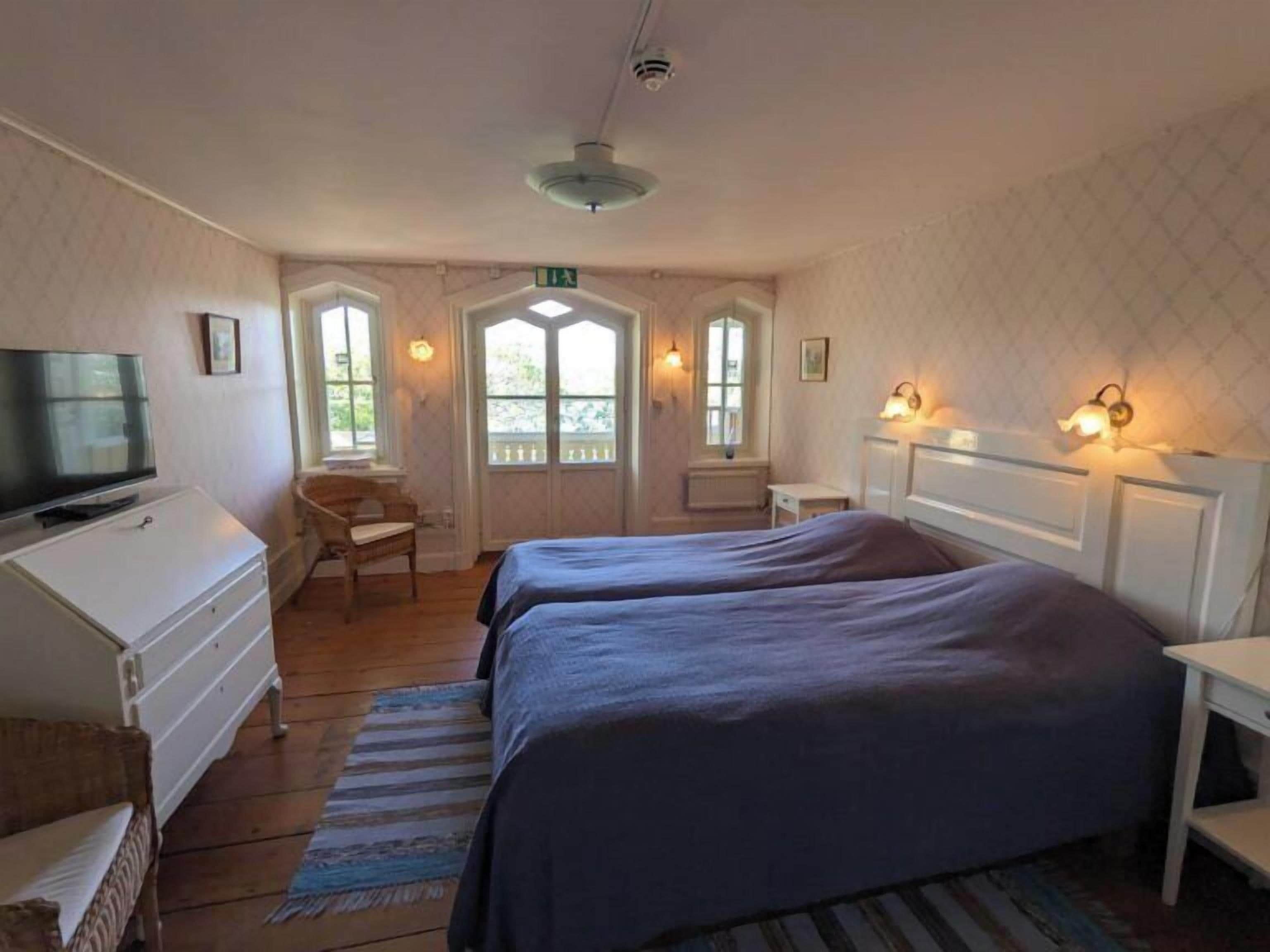 A room with two beds, a television, a desk, and a chair.