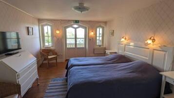 A room with two beds, a television, a desk, and a chair.