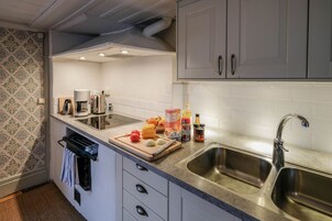Eine Küche mit doppelter Spüle, einer Kaffeemaschine, einem Schneidebrett mit Gemüse und einem Toaster.