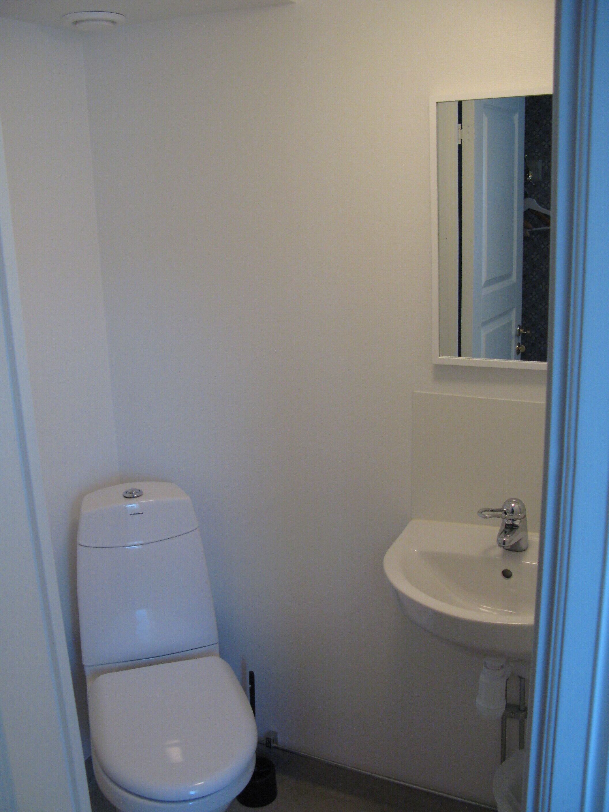 A small, white bathroom with a toilet and a sink.